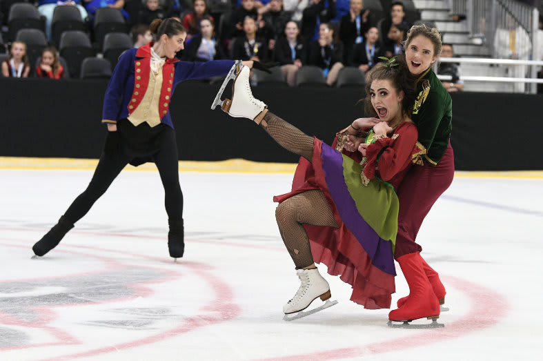 Senior skater holding another skater in a dress who is falling in their arms.